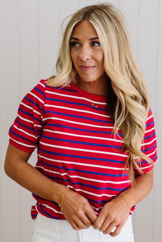 Woman wearing a red and blue striped shirt against a plain background