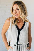 Woman wearing a white sleeveless dress with black trim against a plain background