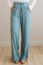 Person wearing teal pants with a white background