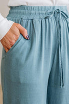 Teal pants with a drawstring waist worn by a person.