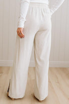 Person wearing white pants and a long-sleeve top against a plain background