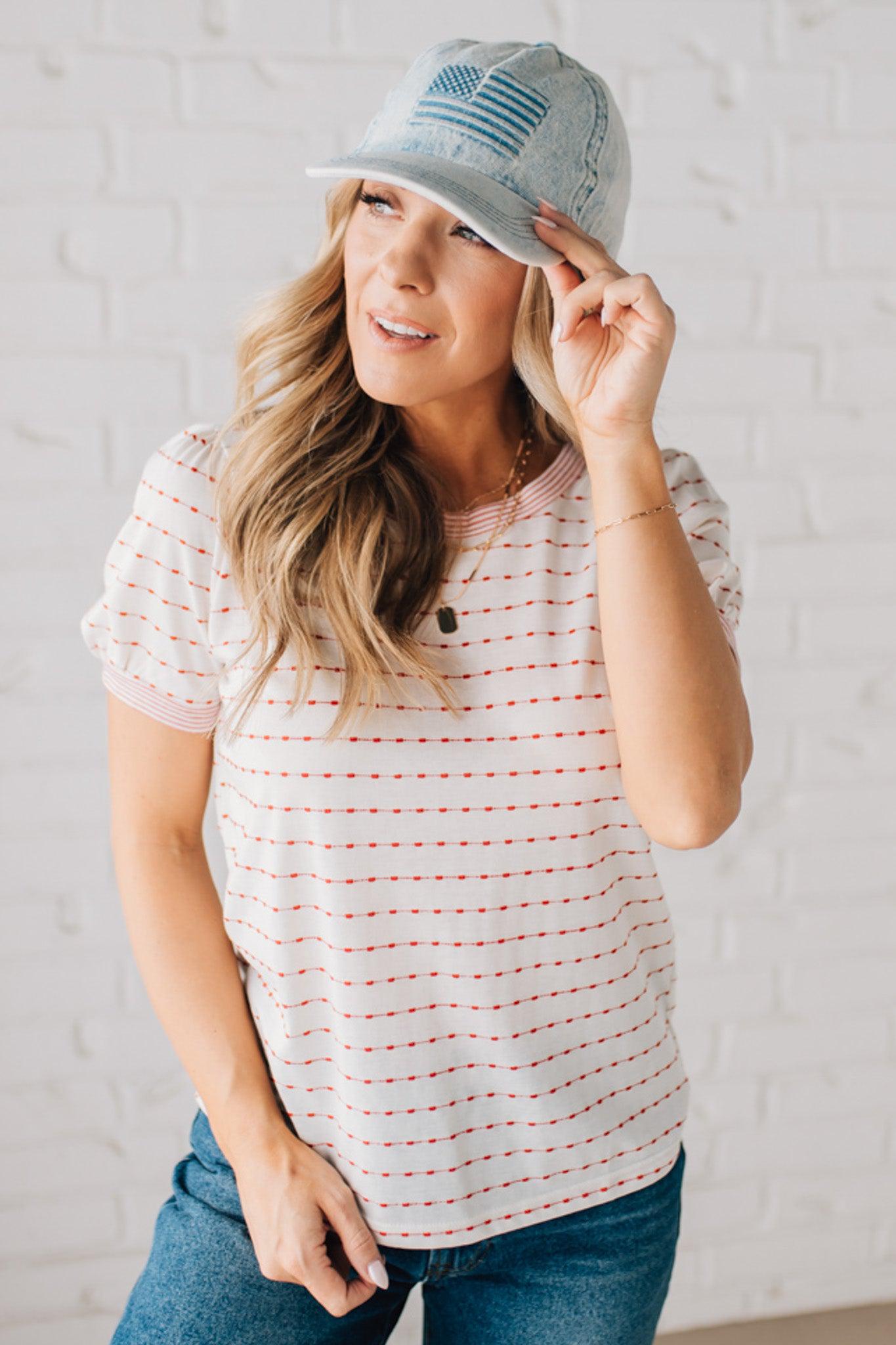 BLONDE WOMAN WEARING A STRIPE CONTRAST TRIMMED, PUFF SHORT SLEEVE, DOTTED STRIPE TOP IN WHITE AND RED.