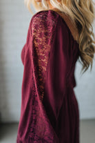 Maroon dress with floral lace detailing on the back, worn by a person with blonde hair.