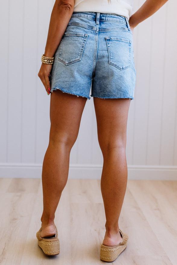 Person wearing light blue denim shorts with a neutral background