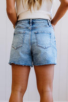 Person wearing light blue denim shorts with a plain background