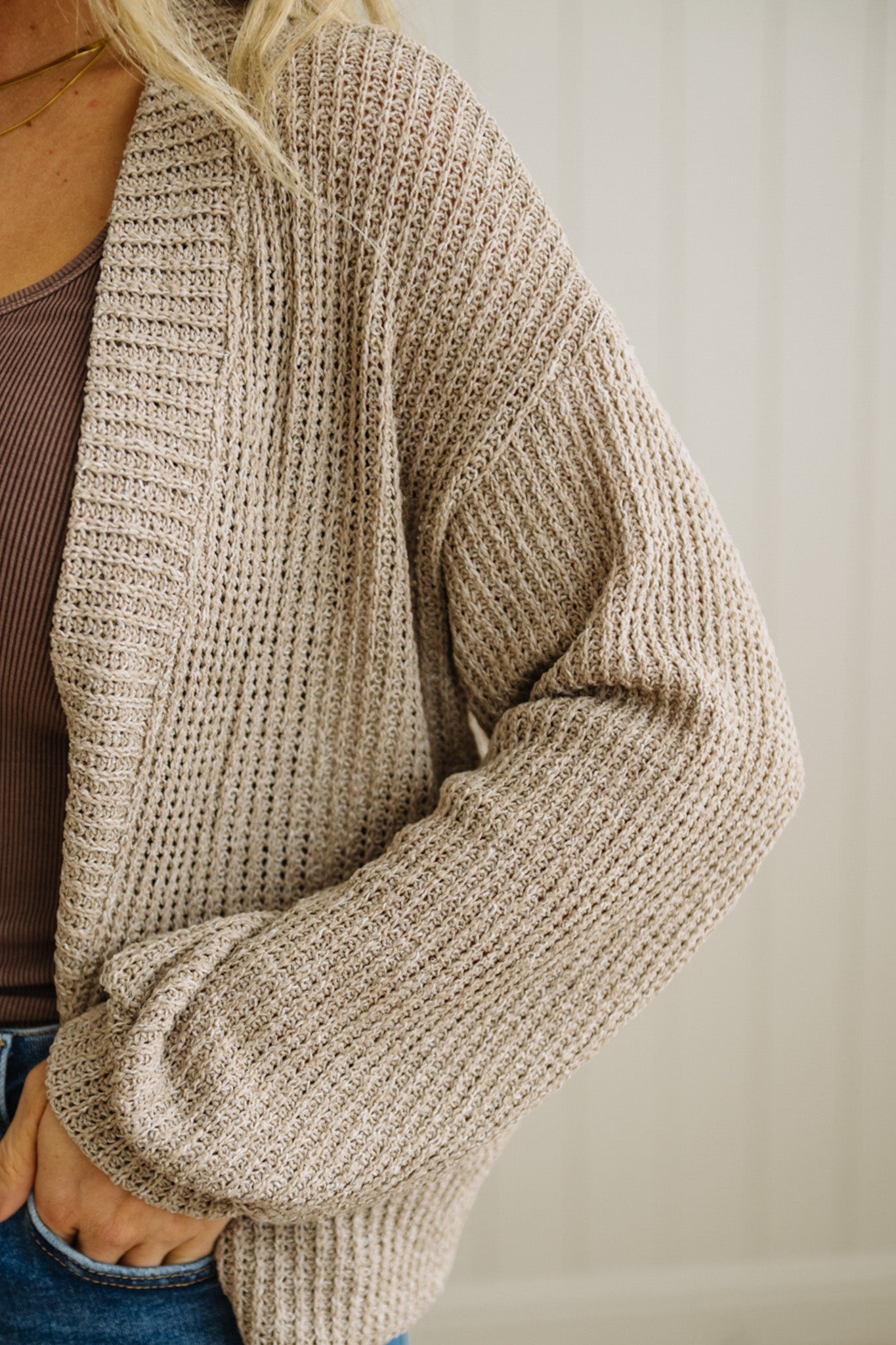 Beige knitted cardigan worn by a person on a plain background