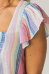 Woman wearing a lightweight ruffle sleeve top with muted rainbow colored vertical stripes.
