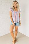 Woman wearing a lightweight ruffle sleeve top with muted rainbow colored vertical stripes.
