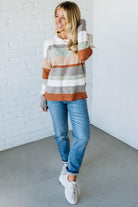 Woman wearing a striped sweater and jeans in a minimal indoor setting