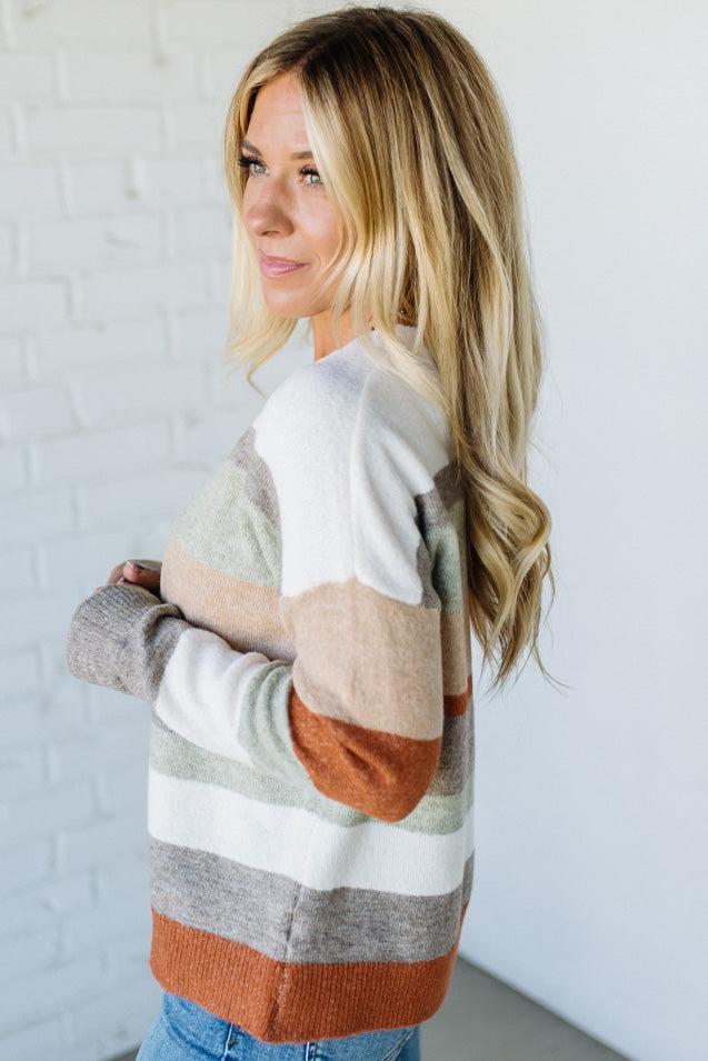 Woman wearing a striped sweater against a white brick wall