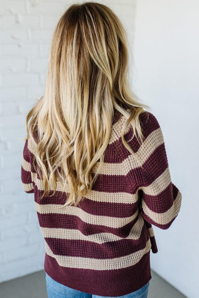 Person wearing a striped sweater with long blonde hair against a white background