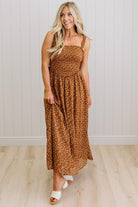 Woman wearing a brown polka dot dress standing against a white paneled wall.