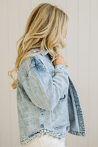 Person wearing a light blue denim jacket against a plain background