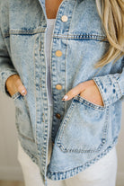Person wearing a light blue denim jacket with a neutral background