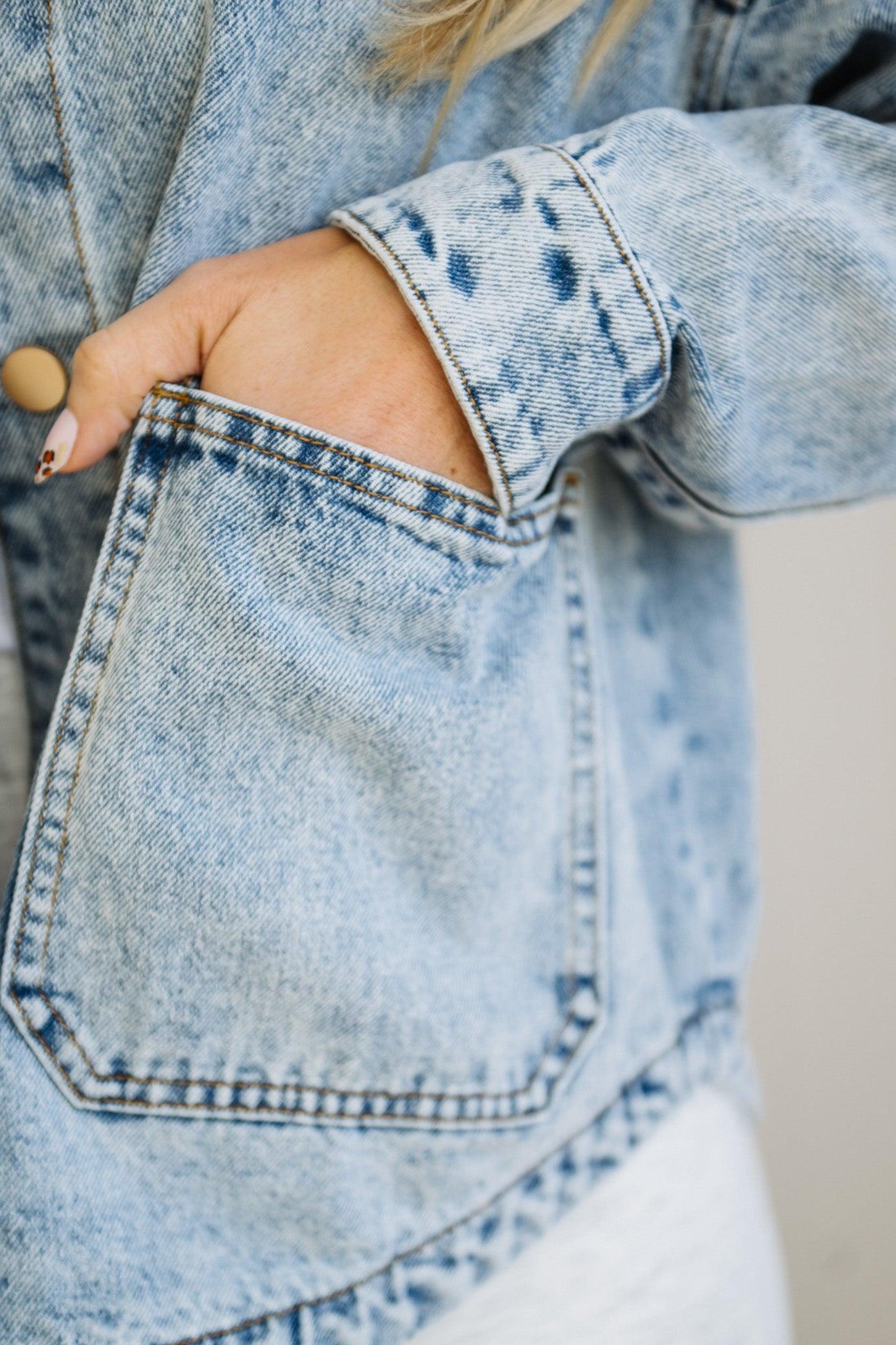 Close-up of a person wearing a light blue denim jacket with a pocket.
