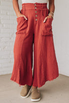 Person wearing red wide-leg pants with a white brick wall background