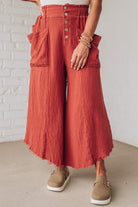 Person wearing red wide-leg pants with a white brick wall background