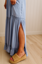 Person wearing a blue dress with a slit, standing on a wooden floor.