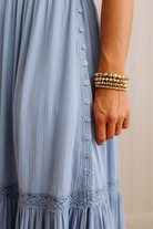 Light blue dress with buttons and lace trim, worn by a person with gold bracelets.
