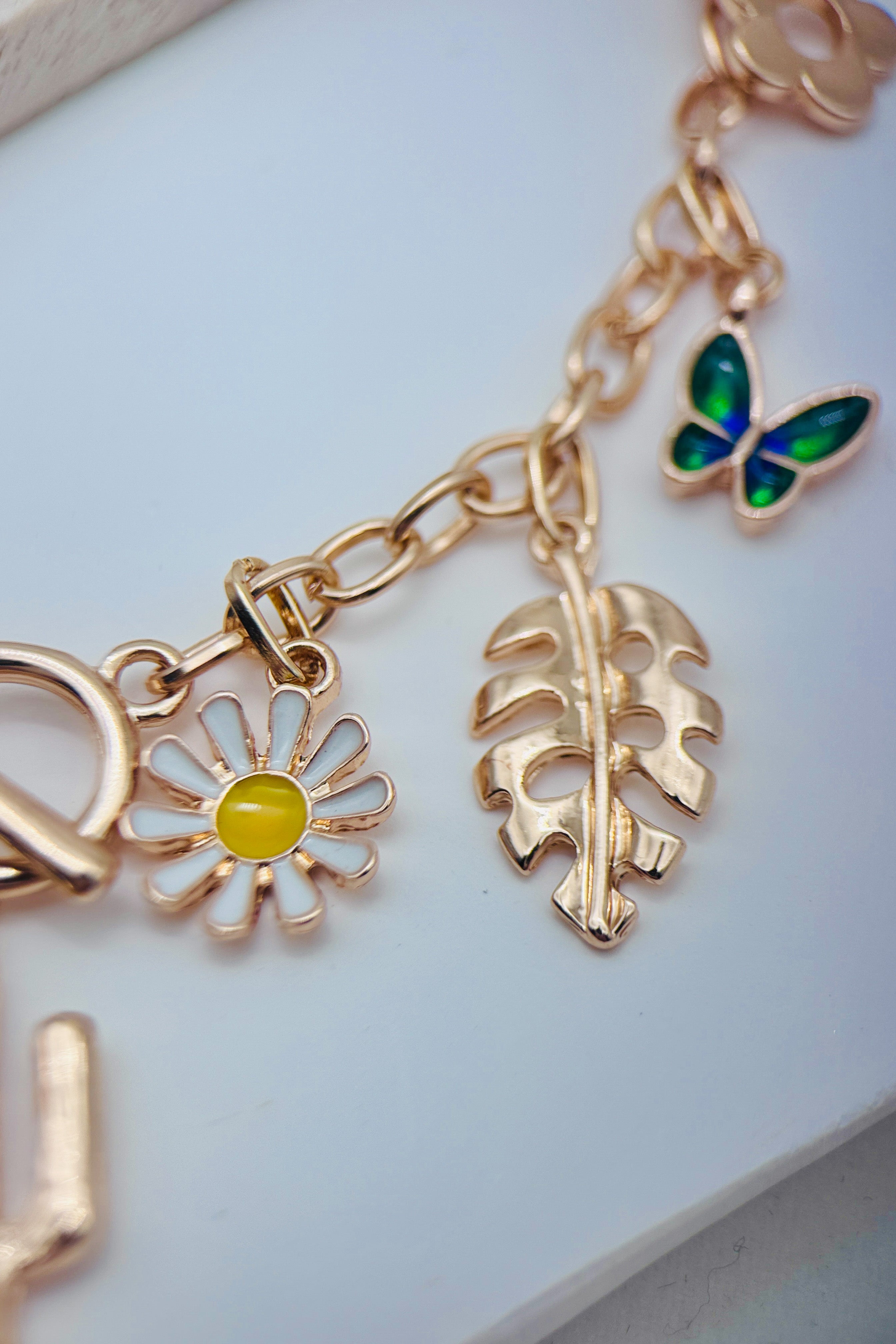 Gold charm necklace with various charms on a light blue background