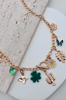 Gold necklace with various charms on a light surface