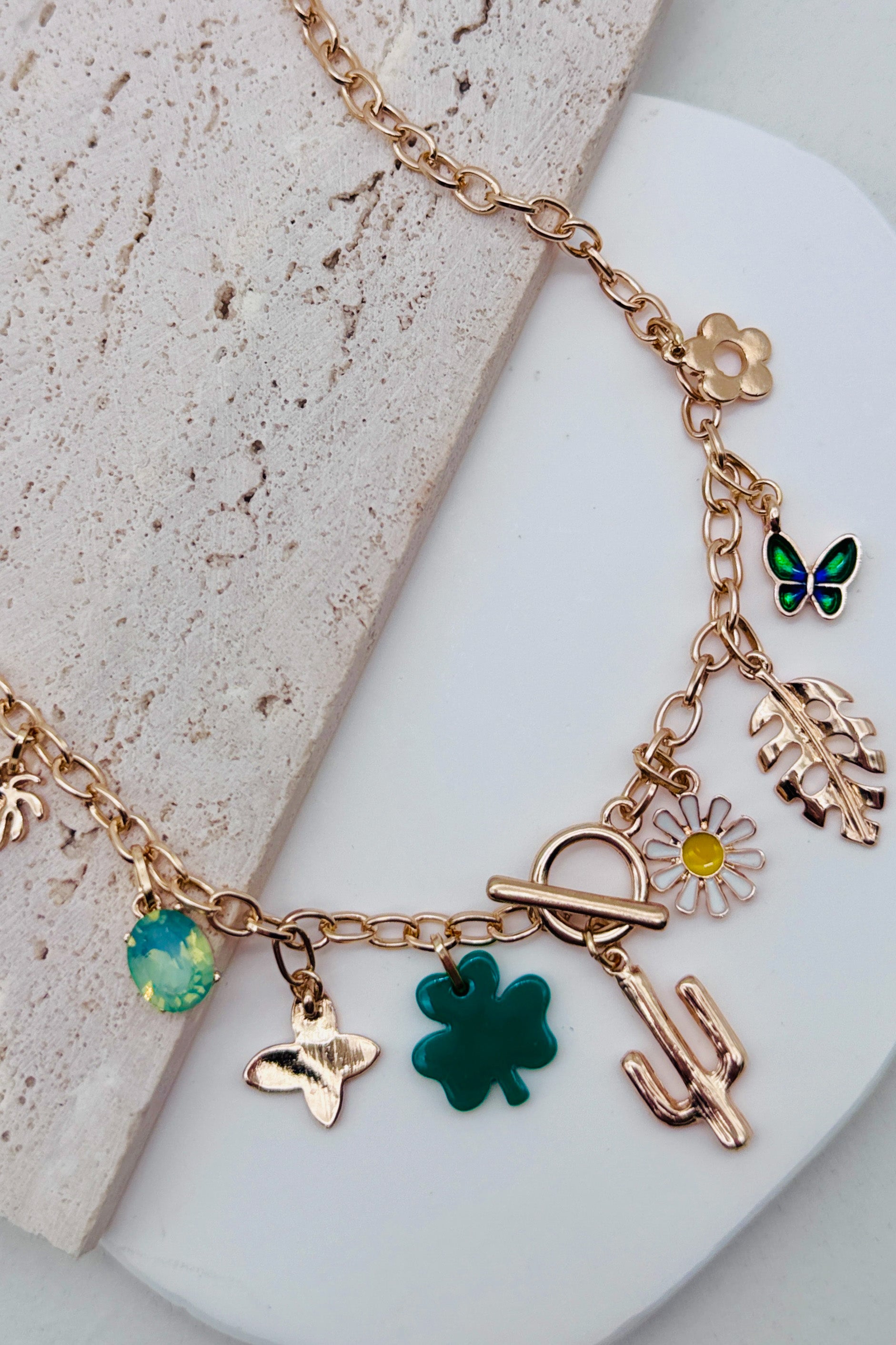 Gold necklace with various charms on a light surface