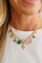 Gold necklace with various charms worn by a person on a white background