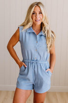 Woman wearing a light blue romper against a neutral background