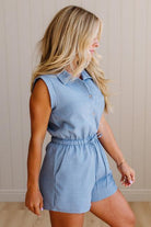 Woman wearing a light blue sleeveless romper against a neutral background