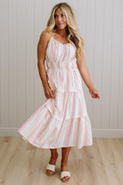 Woman wearing a white dress with red stripes against a light wooden panel background