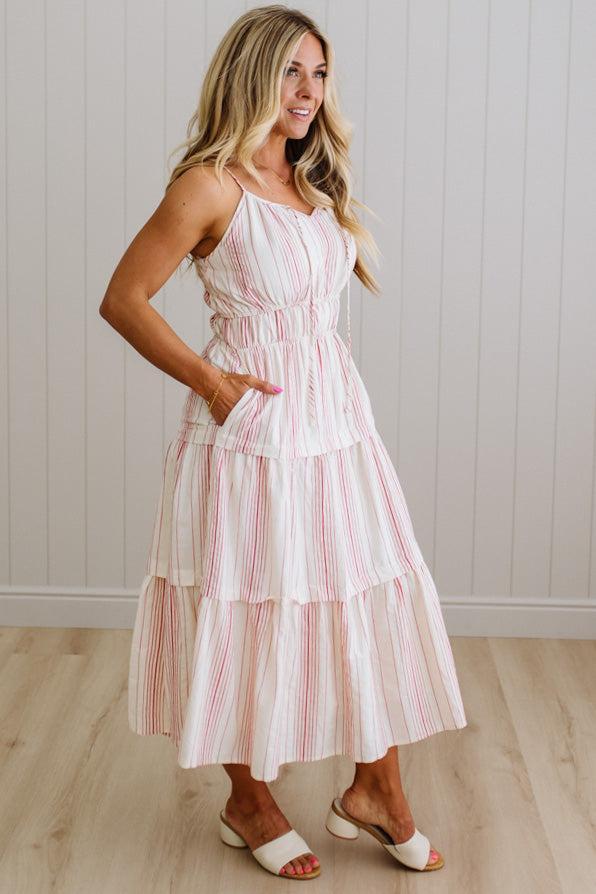 Woman wearing a striped dress standing against a white wall.