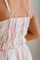 Close-up of a person wearing a white dress with red stripes on a blurred background