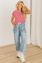 Woman wearing a red and white striped shirt with blue jeans indoors.