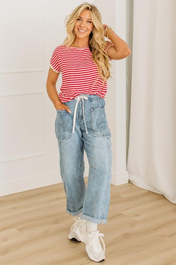 Woman wearing a red and white striped shirt with blue jeans indoors.