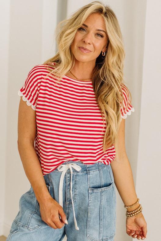 Woman wearing a red and white striped shirt and blue jeans against a plain background