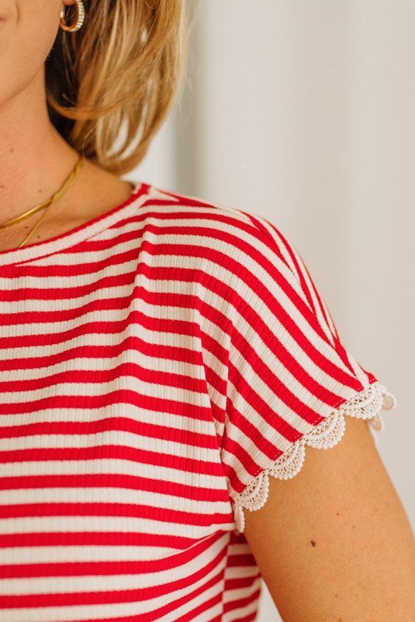 Red and white striped shirt with lace trim sleeves on a plain background