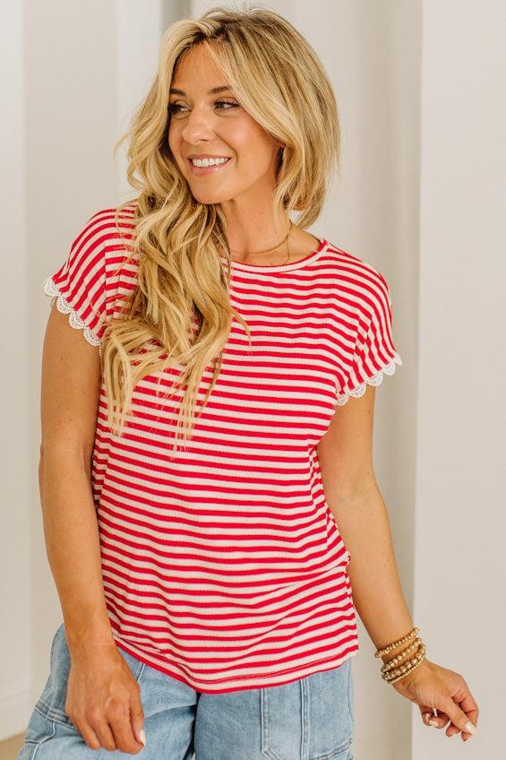 Woman wearing a red and white striped shirt with lace trim sleeves.