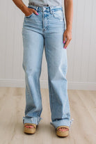 Person wearing light blue jeans standing against a plain background