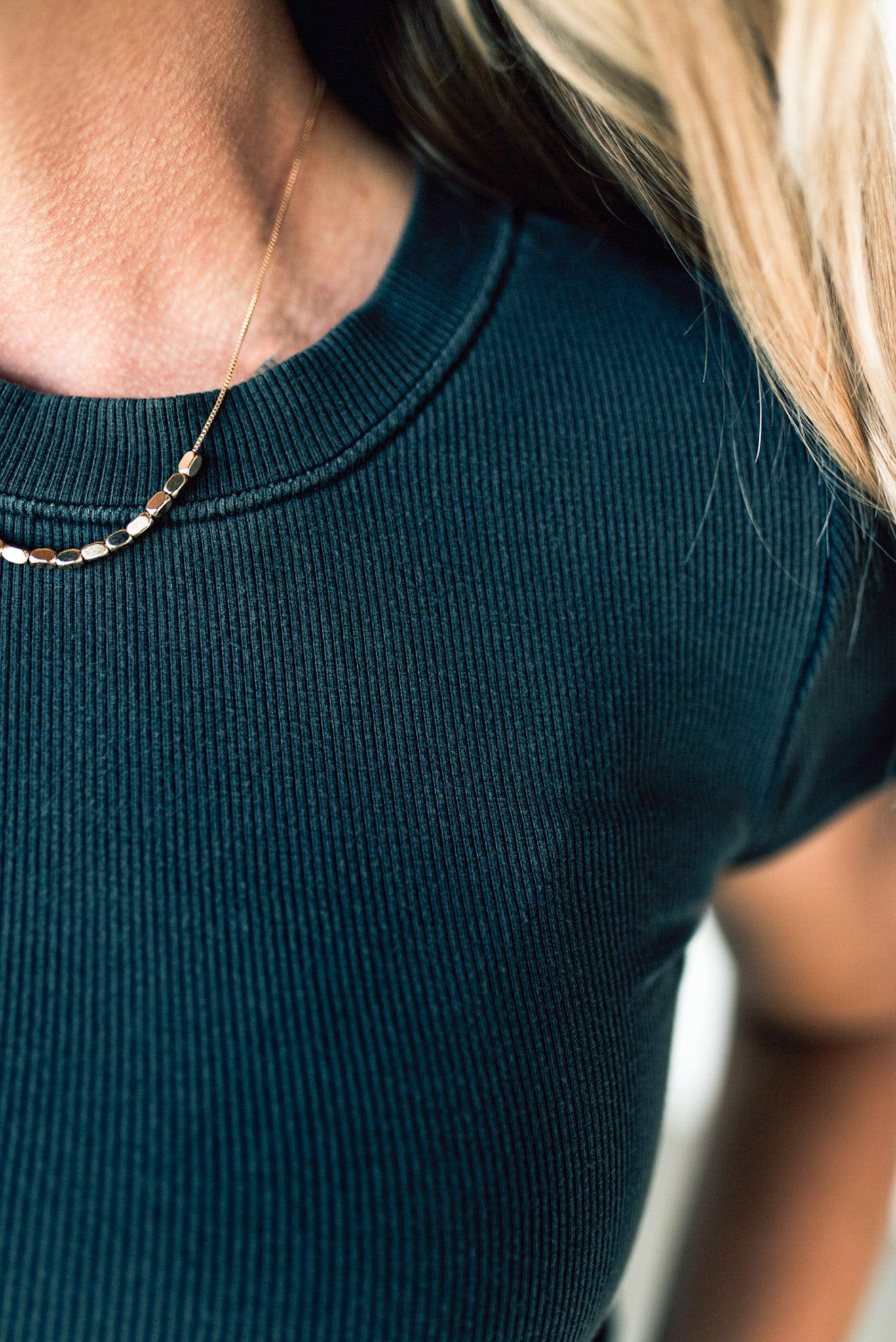 Blonde woman wearing a basic slim fit ribbed tee shirt.