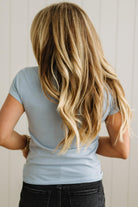 Person with long blonde hair wearing a light blue shirt against a neutral background