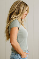 Woman wearing a green t-shirt and blue jeans against a neutral background