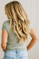 Person wearing a green t-shirt and blue jeans with long blonde hair.