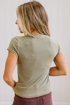 Woman wearing a green t-shirt and brown jeans against a neutral background