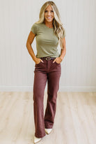 Woman wearing a green t-shirt and brown jeans against a neutral background