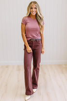 Woman wearing a pink t-shirt and brown jeans against a neutral background