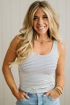 Woman wearing a striped tank top and jeans with a neutral background