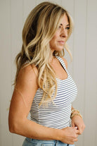 Woman wearing a striped tank top against a neutral background