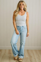 Woman wearing a striped tank top and light blue jeans against a neutral background