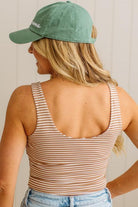 Woman wearing a green cap and striped tank top against a neutral background