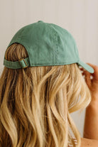 Green cap worn by a person with blonde hair against a neutral background
